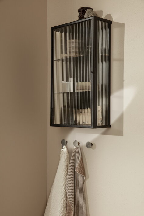 Dizajnová skrinka z čierneho kovu s vlnitým sklom na stene v kúpeľni