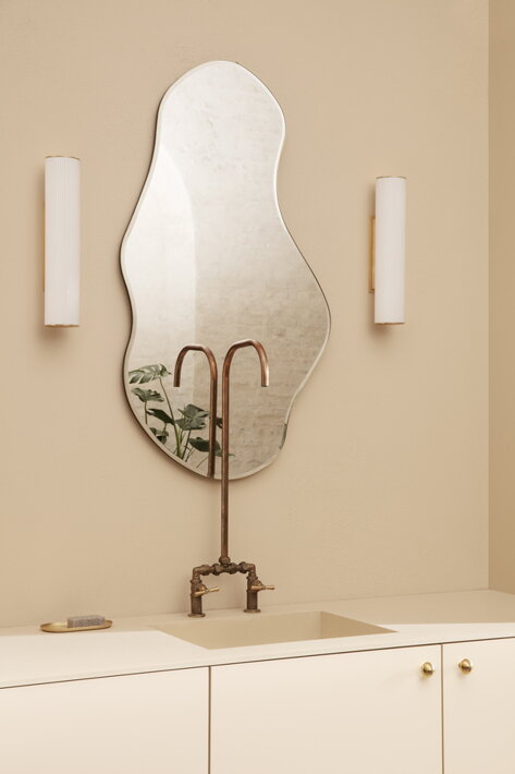 Dve malé nástenné lampy po stranách dizajnového zrkadla v kúpeľni