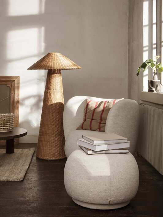 Stojanová lampa z prírodného ratanu pri dizajnovom kresle v obývačke