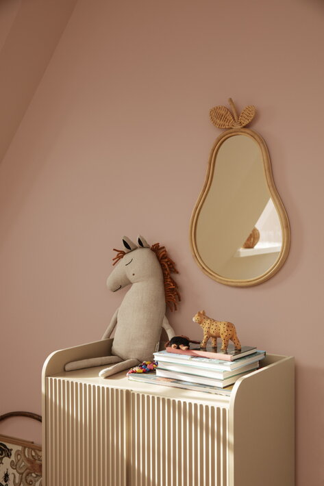 Detské zrkadlo hruška s prírodným ratanovým rámom na stene nad komodou s hračkami