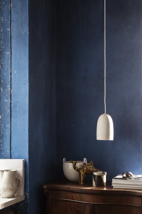 Malá biela lampa z kameniny v jedálni s modrou stenou