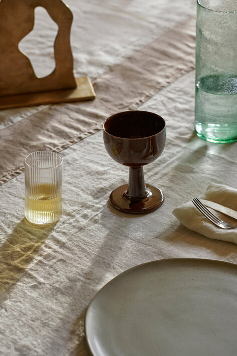 Číry vrúbkovaný pohár s limonádou na stole s keramickou čašou