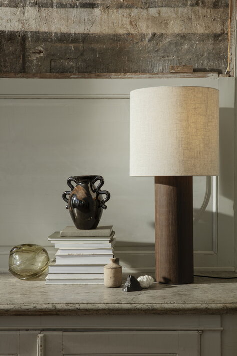 Dizajnová stojanová lampa z hnedého dreva s prírodným tienidlom na komode s vázou
