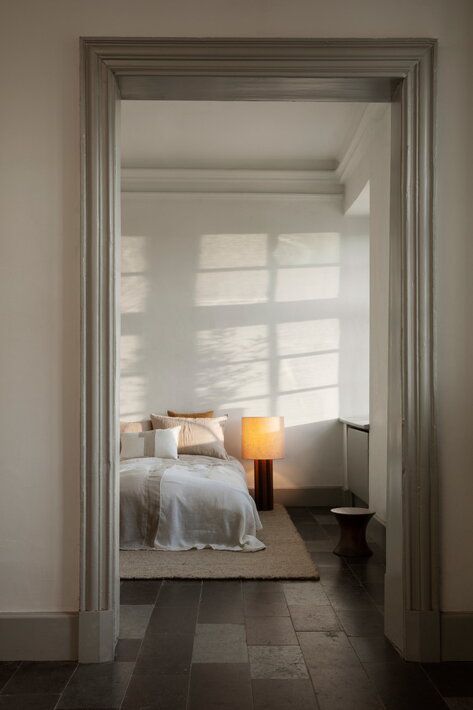 Masívna stojanová lampa z dreva s tienidlom pri posteli v spálni
