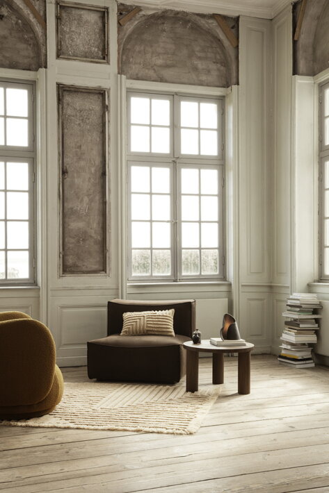 Hnedé dizajnové kreslo s oblými hranami v minimalistickej obývačke