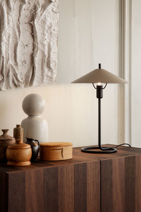 Čierna stolová lampa s kašmírovým tienidlom na drevenej komode