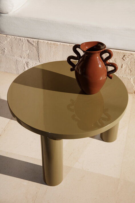 Lesklý okrúhly zelený stolík s dizajnovou vázou