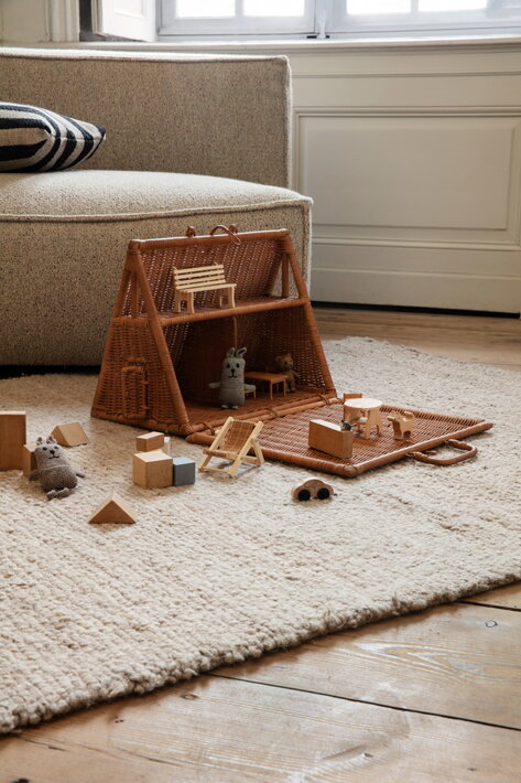 Plyšové a drevené hračky v detskom ratanovom domčeku na podlahe v detskej izbe