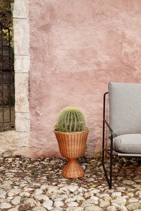 Nízky ratanový stojan s kaktusom na terase pri dizajnovom kresle