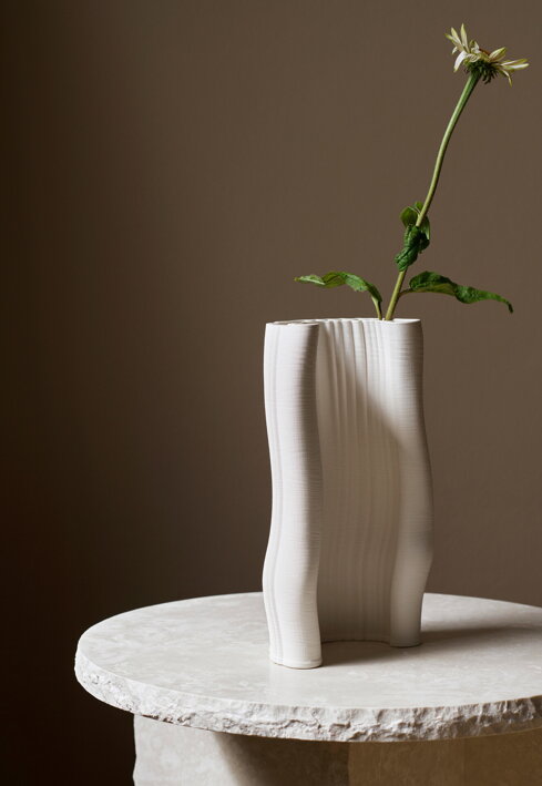 Nepravidelná vrstvená váza z kameniny s jedným kvetom na bielom mramorovom stolíku
