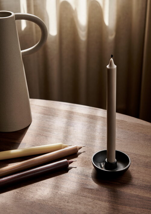Štyri vysoké jednofarebné sviečky v zemitých farbách na stole pri váze