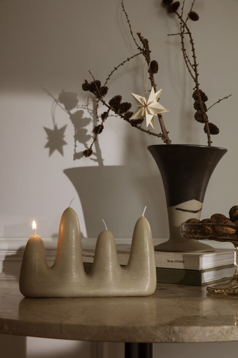 Adventná sviečka so štyrmi knôtmi pri váze s vianočnými dekoráciami