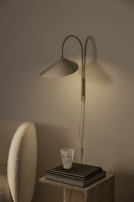 Luxusná nástenná lampa z kašmírového kovu nad dizajnovým kreslom