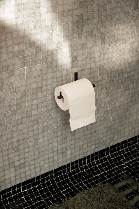 Minimalistický čierny držiak na toaletný papier z práškovaného kovu na mozaikovej stene