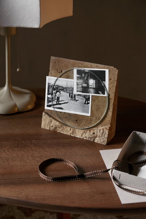 Dizajnový stojan na fotografie z travertínového kameňa a skla na stole v pracovni