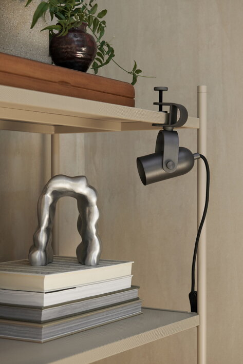 Minimalistická lampička z čierneho kovu s praktickým držiakom na poličke s knihami