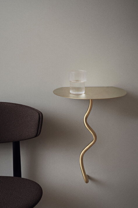 Mosadzný nástenný stolík pri stoličke ako nočný stolík v spálni