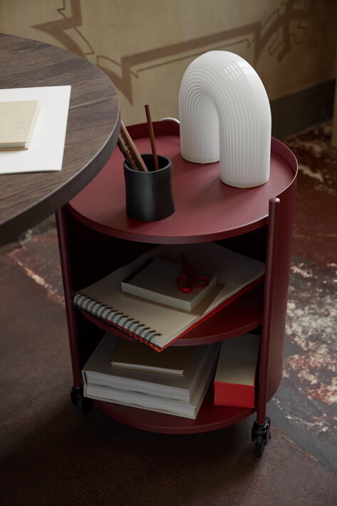 Dizajnový príručný stolík na kolieskach z červeného kovu v pracovni s dizajnovou opálovou lampou