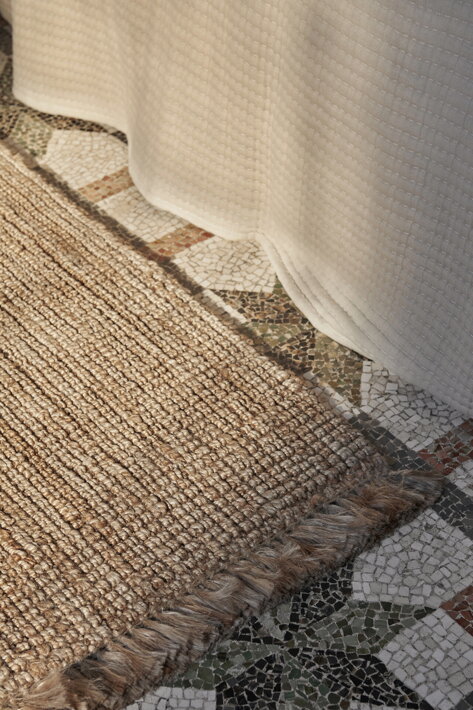 Veľký, ručne tkaný jutový koberec na kamennej podlahe v predsieni