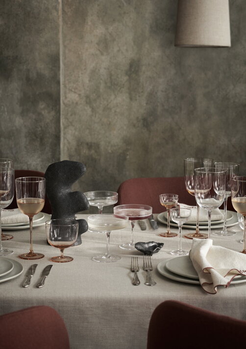 Stopkové ružové poháre na biele víno na stole s jedlom