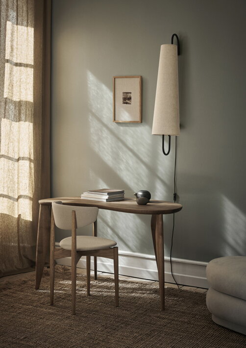 Nástenné svietidlo s čiernym železným rámom a textilným tienidlom v prírodnej farbe pri stolíku v obývačke