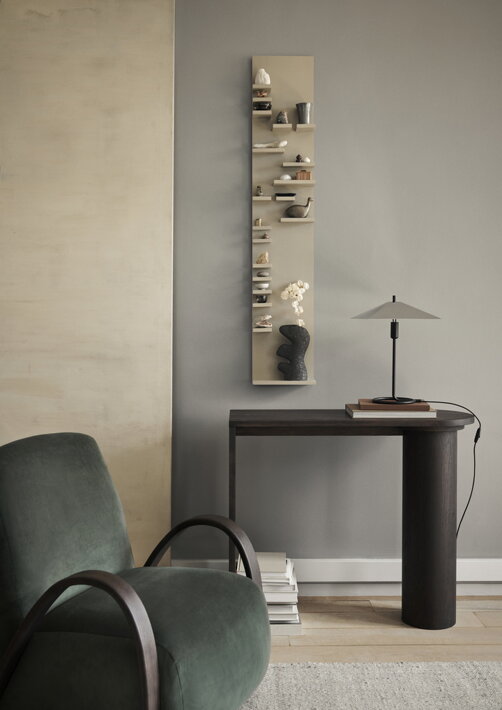 Luxusné tmavozelené dizajnové kreslo v obývačke pri stolíku s lampou pred stenou s obrazom