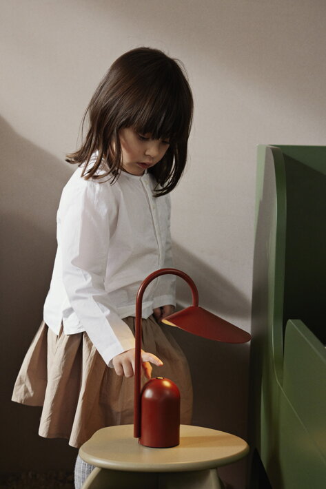 Dievčatko s prstom nad trojstupňovým dotykovým stmievačom lampy