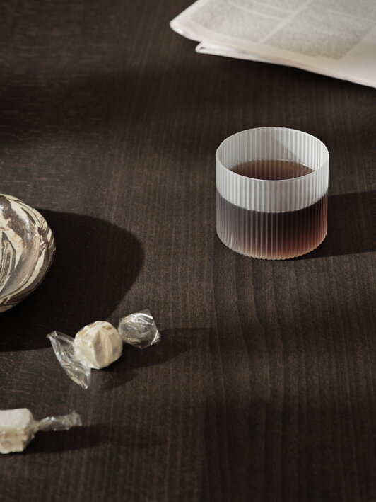 Naliaty nápoj v nízkom matnom pohári položenom na stole