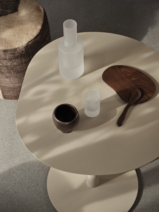 Matná karafa a pohár na stolíku s ďalšími doplnkami stolovania
