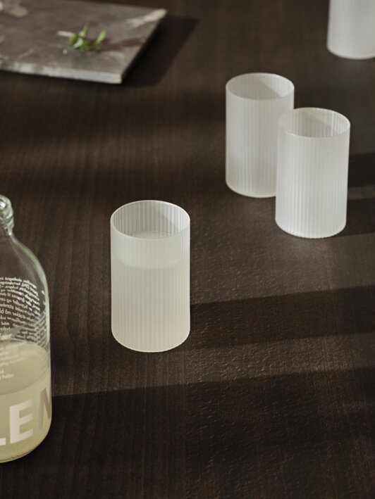 Matné poháre na stole, pričom v jednom je naliaty nápoj