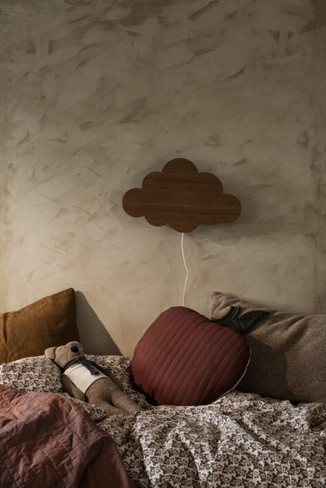 Destká hnedá lampa obláčik nad detskou posteľou s prešívaným vankúšom a plyšákom
