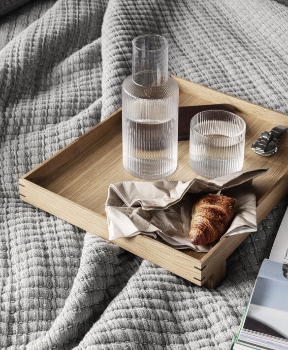 Menšia karafa a pohár s vodou na podnose s raňajkami do postele