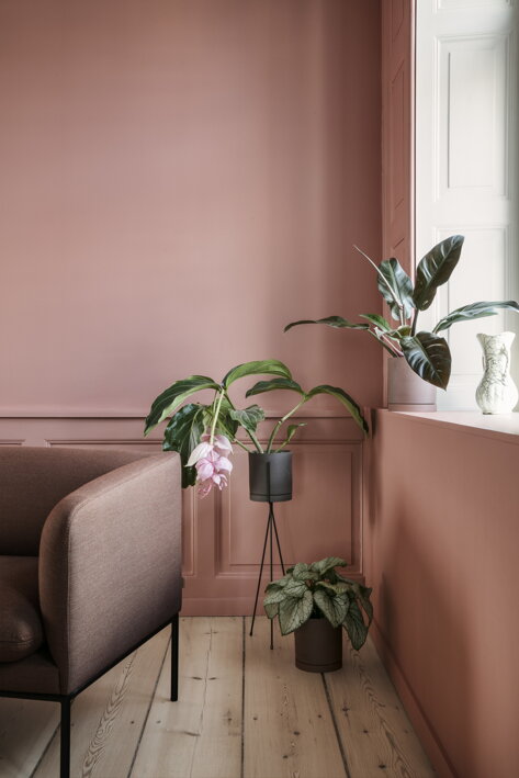 Menší tmavosivý kvetináč z kameniny na kovovom stojane v obývačke