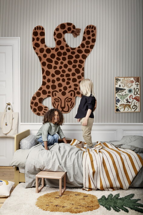 Vlnený koberec v tvare leoparda visiaci na stene nad detskou postelou