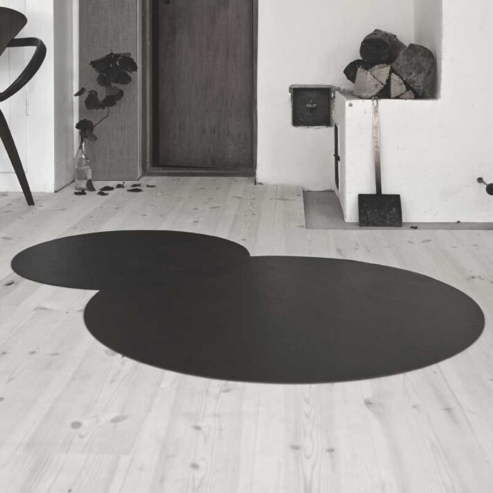 Čierny dizajnový koberec z recyklovanej kože na podlahe v obývačke