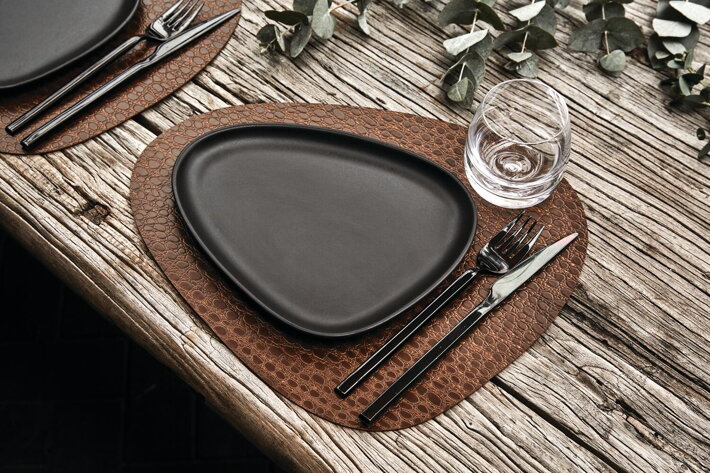 Malý čierny tanier z kameniny na slávnostne prestrenom stole