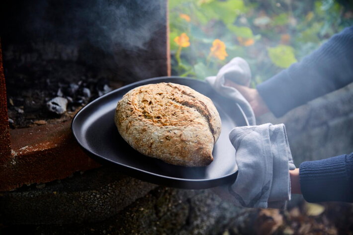 Horúci čerstvý chlieb na čiernom servírovacom tanieri z kameniny
