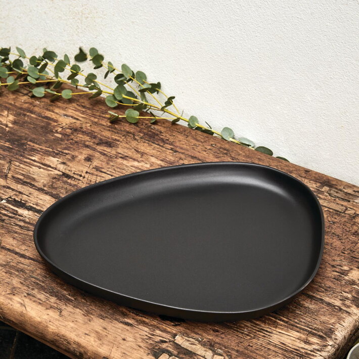 Veľký čierny servírovací tanier na drevenej doske