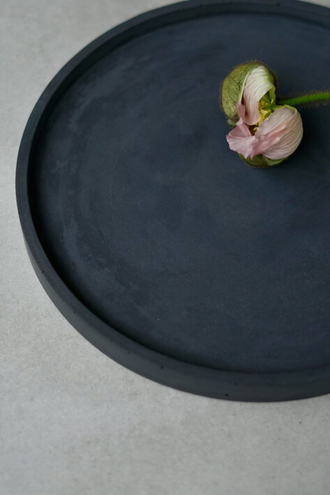 Kvet na čiernom dizajnovom betónovom podnose