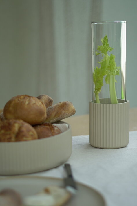 Minimalistická váza z betónu na stole pri betónovej mise s pečivom