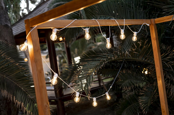 Biela svetelná girlanda s LED žiarovkami na záhradnej pergole