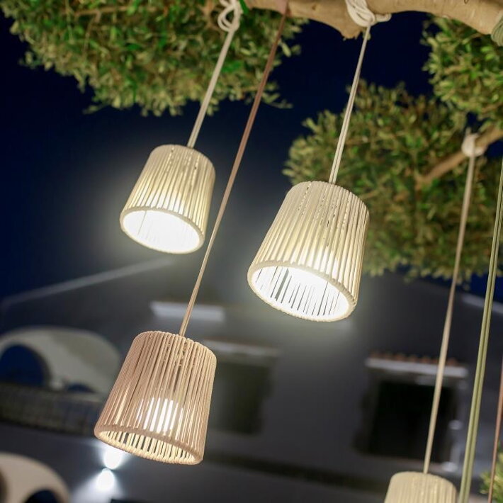 Mini závesné lampy svietiace na konároch stromu vo večernej atmosfére
