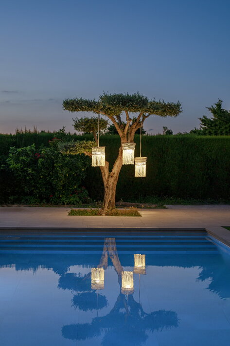 Tri závesné lampy na strome, pred ktorým je bazén