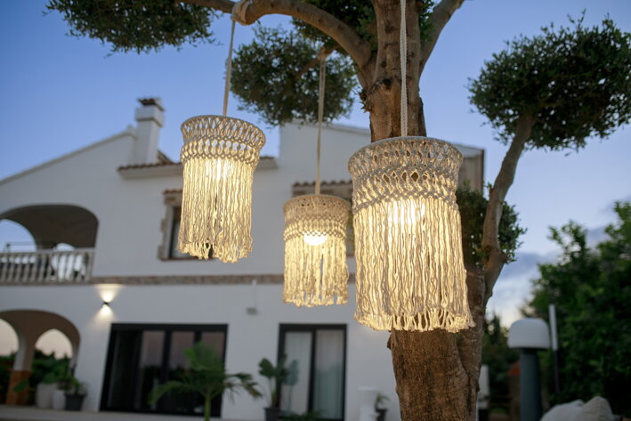 Detail troch závesných lámp so zapnutým svetlom zavesených na strome