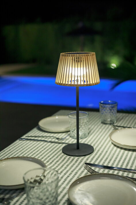 Prenosná lampa umiestnená na stole v záhrade