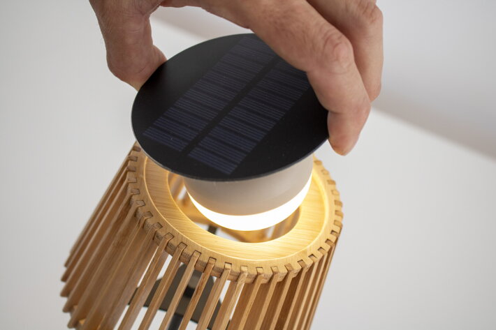 Detailný pohľad na ruku, ktorá umiestňuje solárny panel do lampy