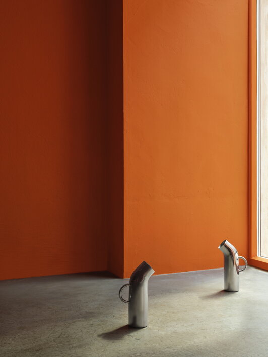 Dva dizajnové džbány z antikoru pri oranžovej stene