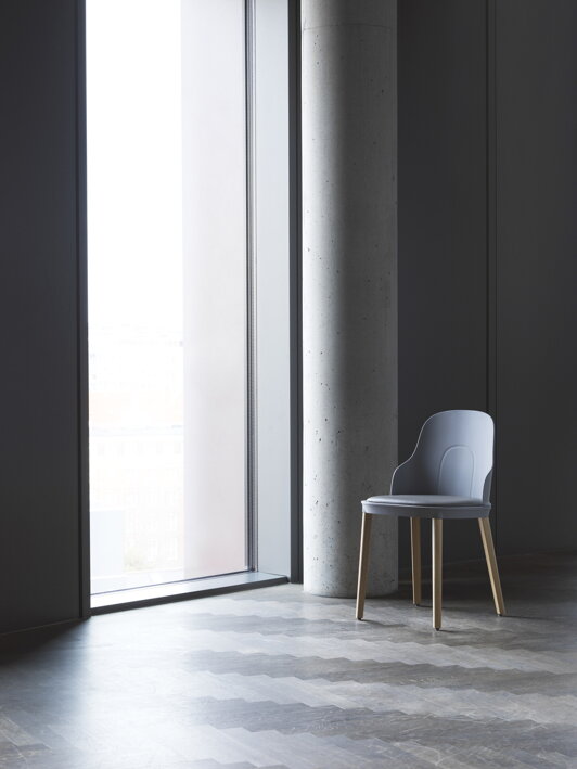 Sivá stolička s dubovými nohami a s čalúnením z kože pri okne