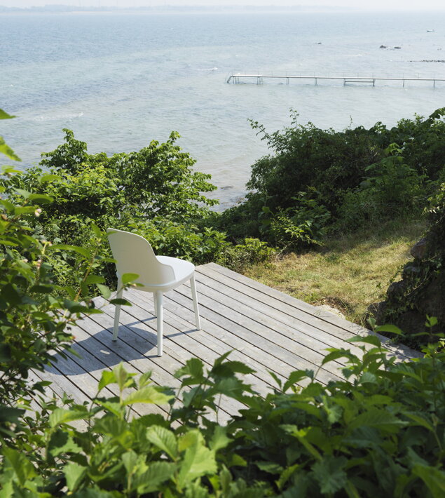 Opustená stolička na terase so zeleňou pri mori