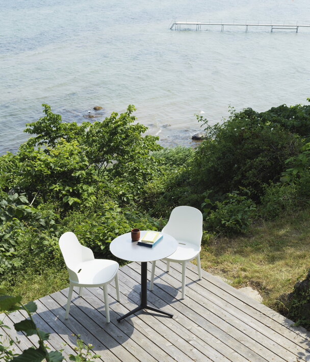 Malý okrúhly kaviarenský stôl na s 2 stoličkami na drevenej terase s výhľadom na more